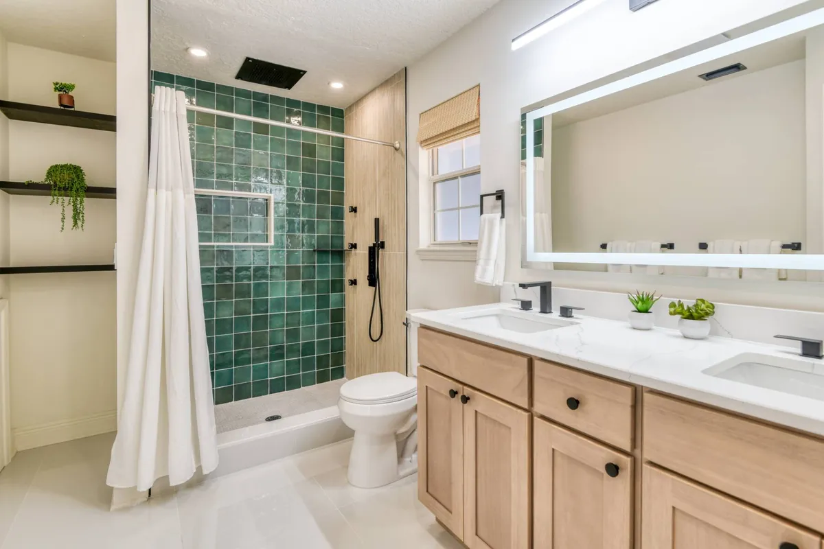 Bathroom with green tile walk-in shower and double vanity