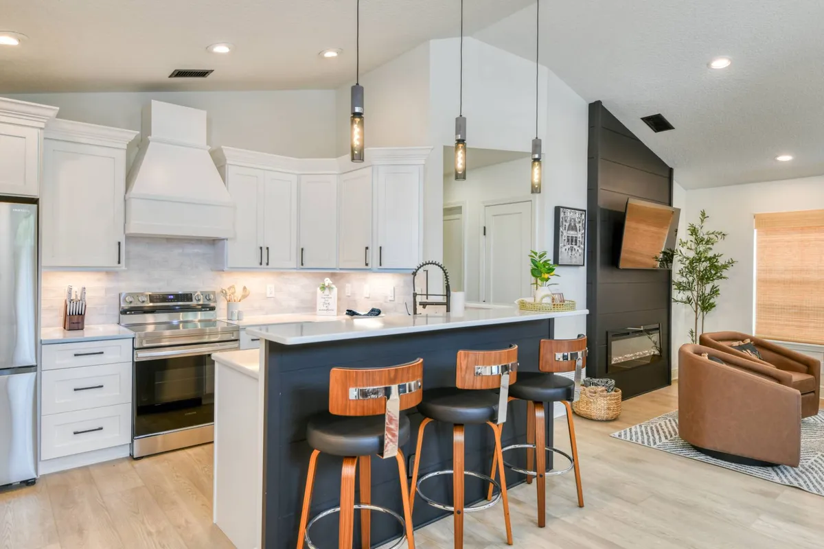 Full kitchen with navy island and leather barstools at Madison By The Sea